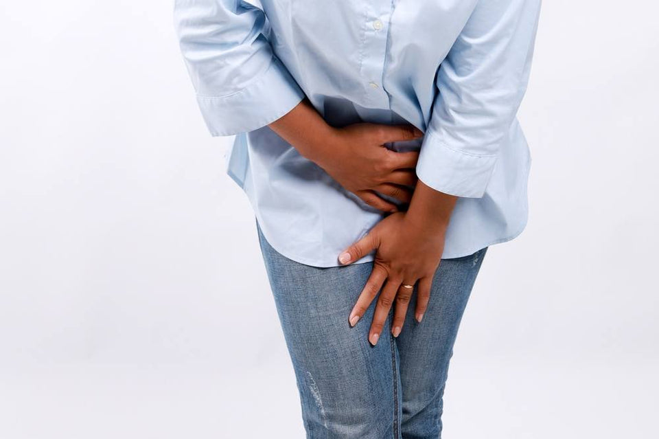 A close-up shot of a woman holding her lower stomach with a hand, experiencing sexual incontinence.