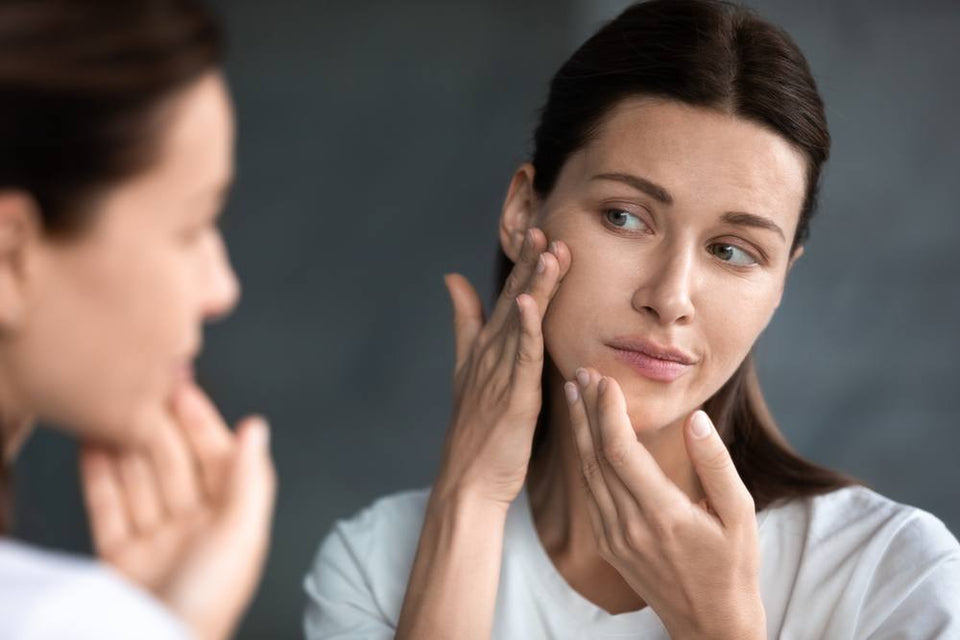 A woman checking her skin in the mirror